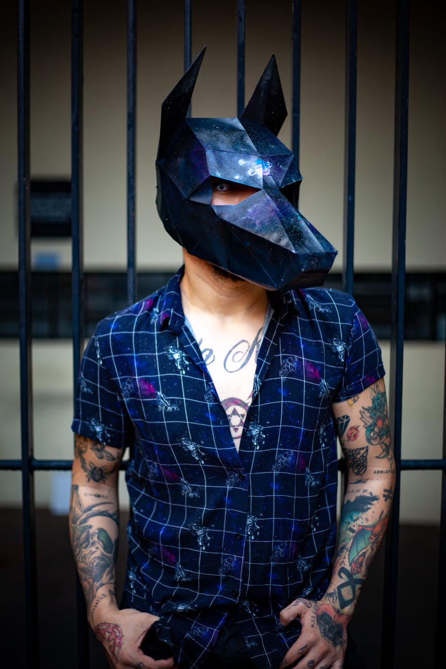 photo of tattooed man wearing black doberman mask